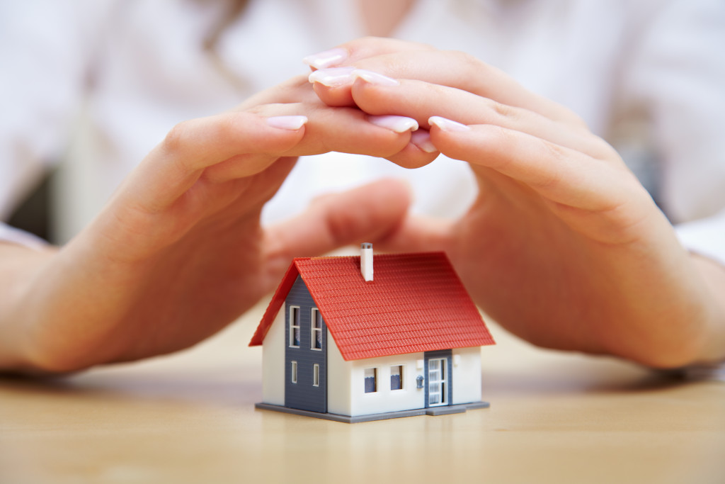 hands covering miniature house